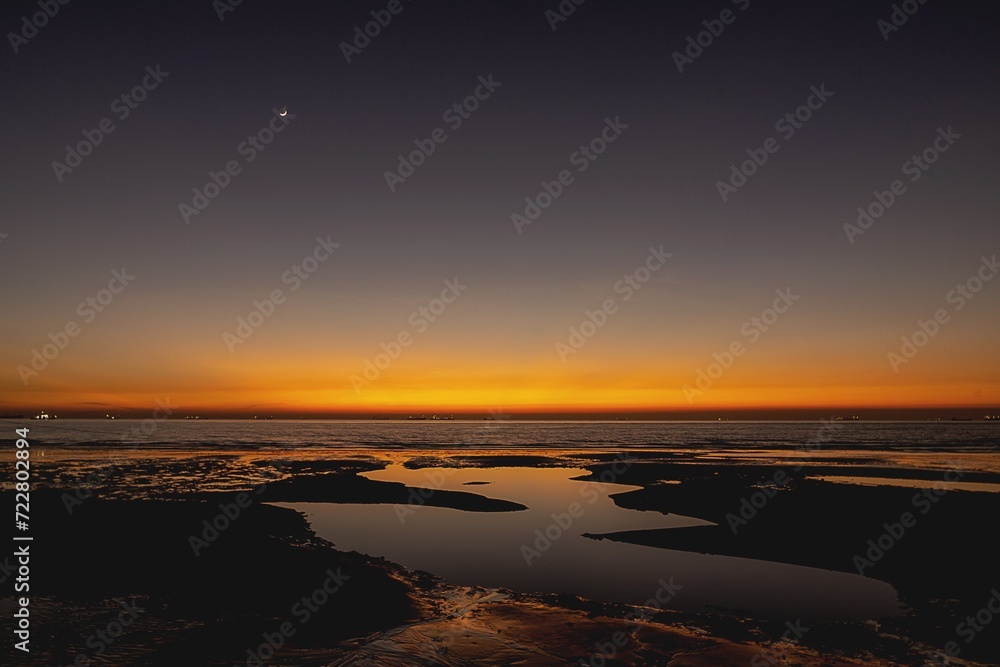 Fototapeta premium A stunning sunset over the Bay of Bengal, with the sky ablaze in rich shades of orange, gold and deep purple as the sun sets behind the horizon.