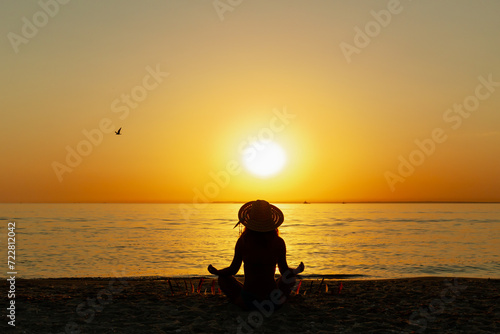 Young woman on tropical beach doing yoga meditating in lotus position at sunset. Serenity and yoga  meditation