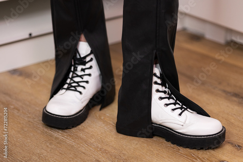 Trendy military white rough boots on high platform with laces, eco-leather skinny with slits at home in dressing room. Female fashion, shoes still life. Front view, seasonal, style, decluttering © Елена Бабанова