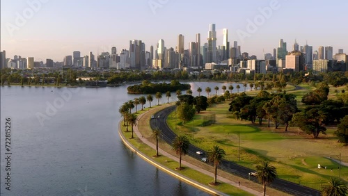 Aerial: Australia Melbourne City Center in Background Evening Golden Hour Flight over Beautiful Albert Park Lake