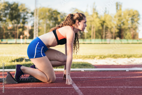 Focused female athlete prepared to run on an athletics track