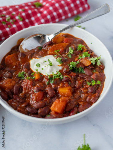 Healthy bean stew with kidney beans, sweet potatoes and vegetables on a plate on light background