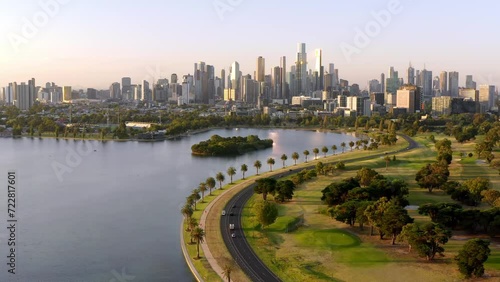 Aerial: Australia Melbourne City Center in Background Evening Golden Hour Flight over Beautiful Albert Park Lake