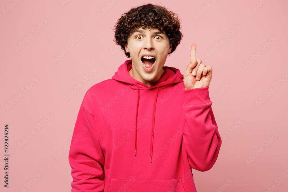 Young insighted smart proactive Caucasian man wears hoody casual clothes holding index finger up with great new idea isolated on plain pastel light pink background studio portrait. Lifestyle concept. Young insighted smart proactive Caucasian man wears hoody casual clothes holding index finger up with great new idea isolated on plain pastel light pink background studio portrait. Lifestyle concept.