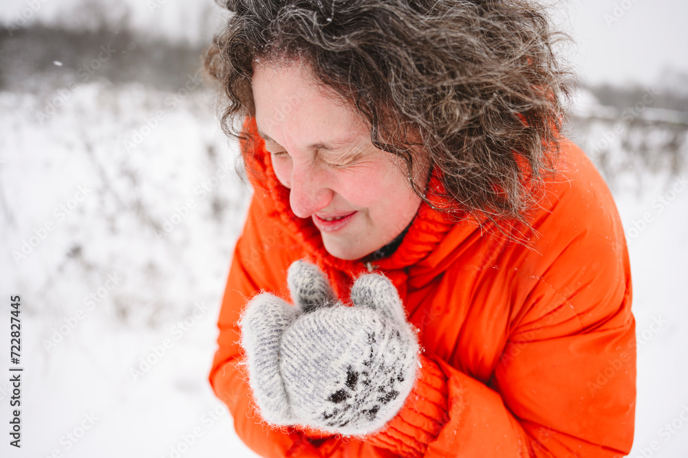 Mature woman shivering in snowfield wearing mittens Mature woman shivering in snowfield wearing mittens