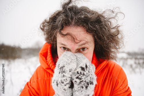 Mature woman covering face with hands in mittens photo
