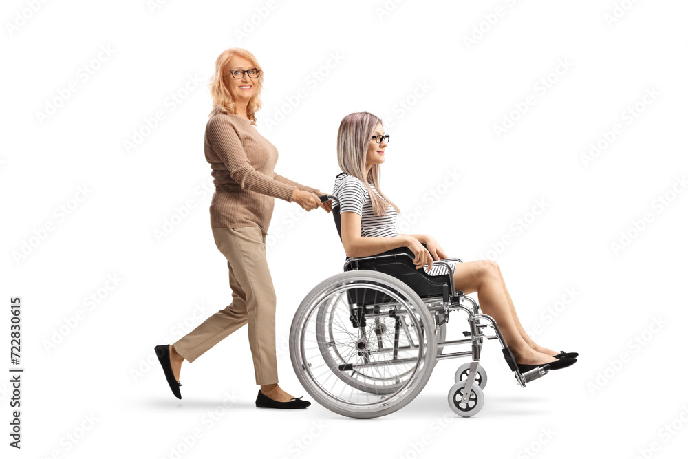 Middle aged woman pushing a younger woman in a wheelchair Middle aged woman pushing a younger woman in a wheelchair