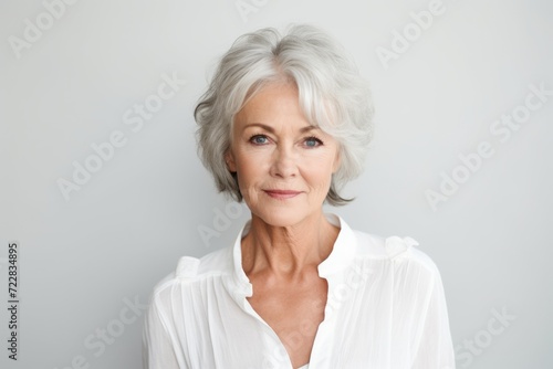 Portrait of beautiful senior woman looking at camera against grey background.
