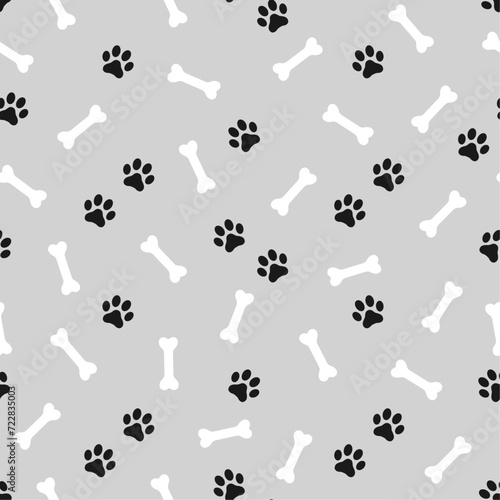 Fototapeta Naklejka Na Ścianę i Meble -  Black domestic pet's paws prints and white bones on gray background. Vector seamless pattern.