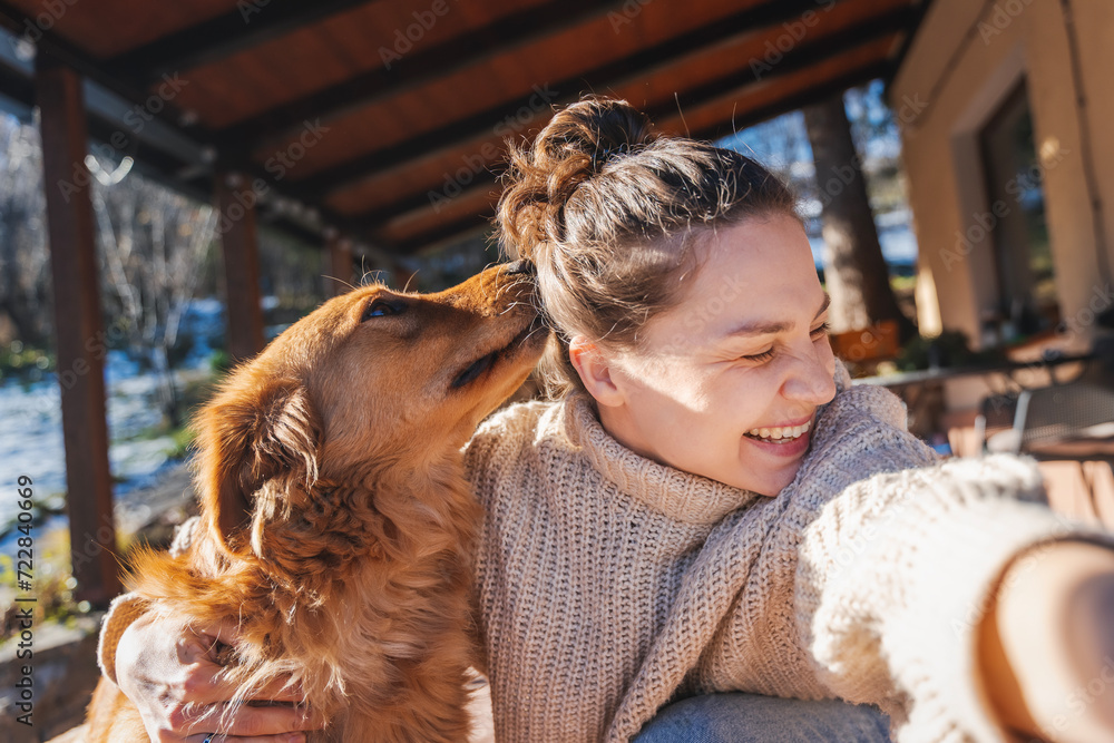 Happy young woman with her labrador retriever dog taking selfie while hugging, spending joyful time together