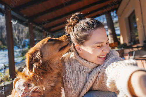 Happy young woman with her labrador retriever dog taking selfie while hugging, spending joyful time together