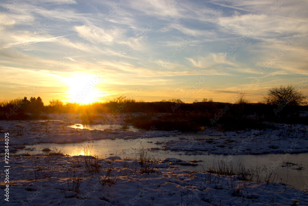 Sunset on snowy meadow on a cold winter day