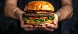 Human hand holding a tasty double beef burger on black background. Generated AI image