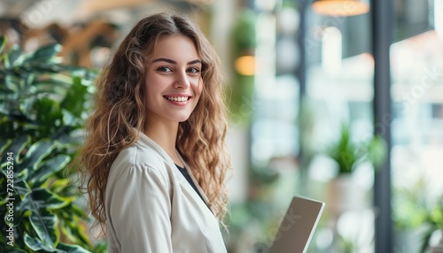 Smiling young businesswoman with laptop in a modern office