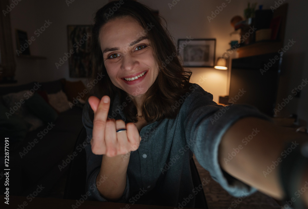 Young happy smiling Caucasian woman making a heart with her fingers at home interior background Young happy smiling Caucasian woman making a heart with her fingers at home interior background