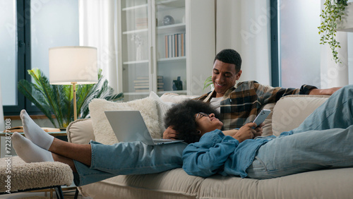 Foto Chilling African American relaxed couple on couch at home together gadget intern
