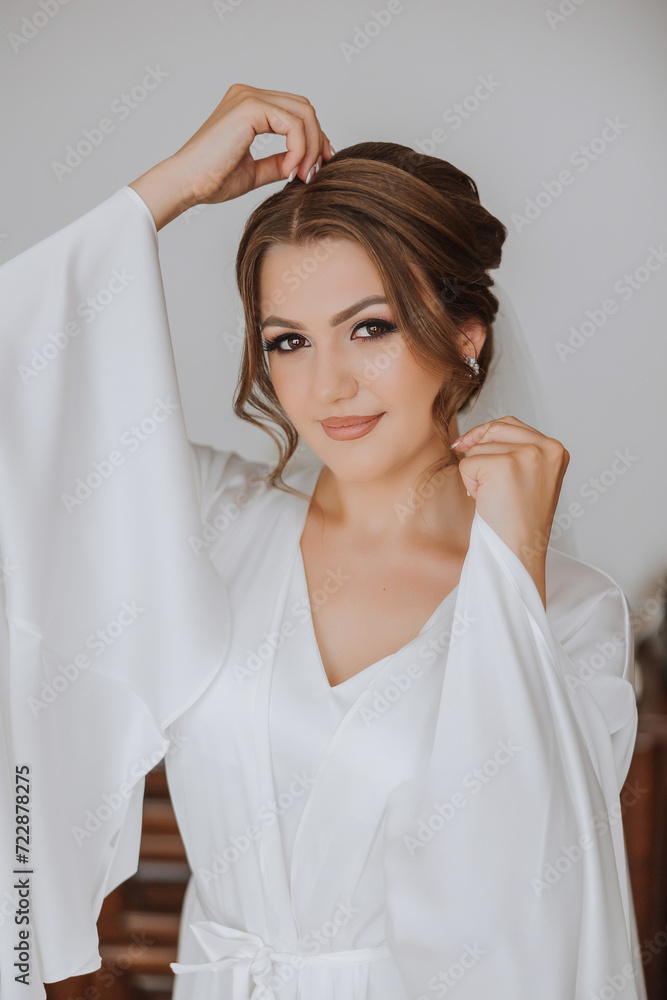 Beautiful bride in a dressing gown in the morning before the wedding ceremony. Incredible hairstyle of the bride. Natural and modern makeup. Portrait of a young bride in a dressing gown. Beautiful bride in a dressing gown in the morning before the wedding ceremony. Incredible hairstyle of the bride. Natural and modern makeup. Portrait of a young bride in a dressing gown.