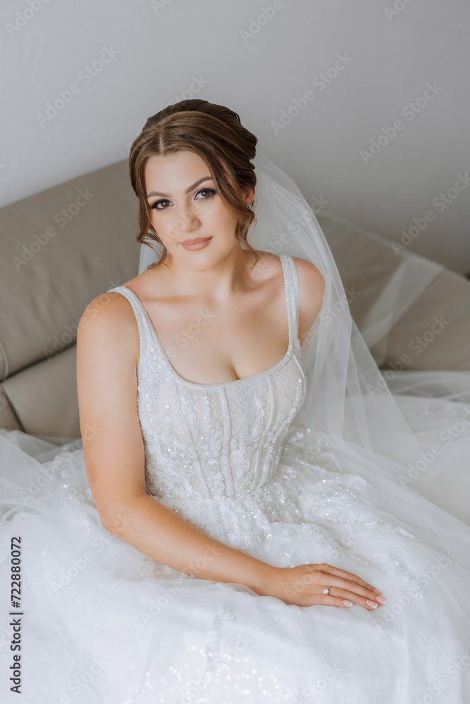Portrait of the bride in the hotel room. A beautiful young girl is dressed in a white wedding dress. Modern wedding hairstyle. Natural makeup. Portrait of the bride in the hotel room. A beautiful young girl is dressed in a white wedding dress. Modern wedding hairstyle. Natural makeup.
