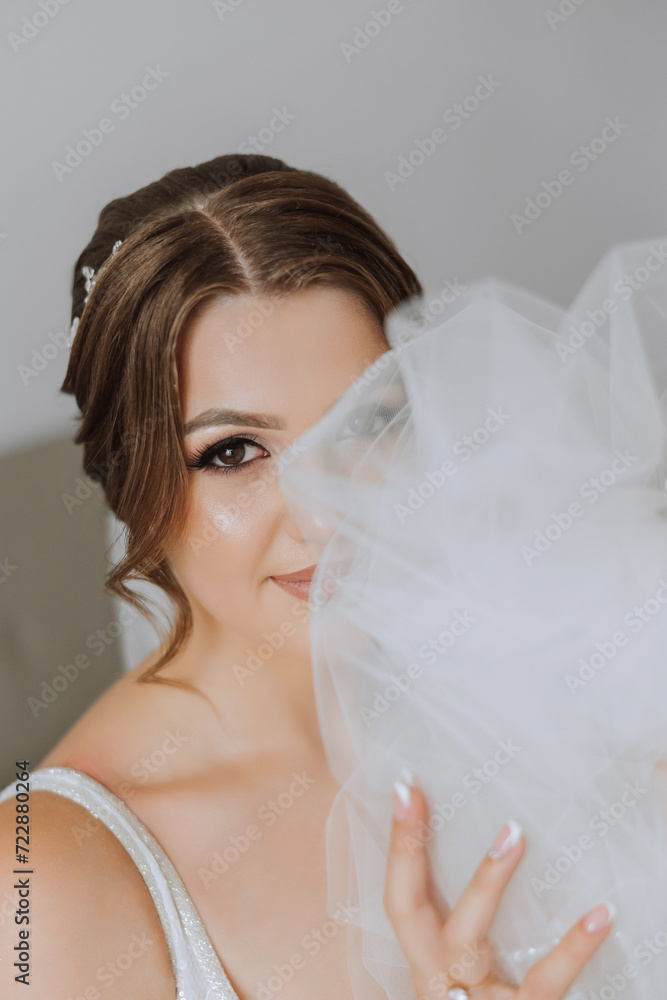 Portrait of the bride in the hotel room. A beautiful young girl is dressed in a white wedding dress. Modern wedding hairstyle. Natural makeup. Portrait of the bride in the hotel room. A beautiful young girl is dressed in a white wedding dress. Modern wedding hairstyle. Natural makeup.
