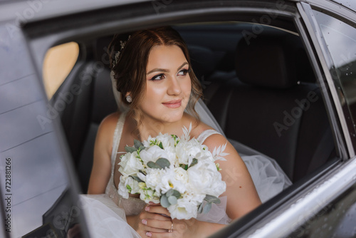 The bride looks out of the car window. Close-up portrait of a pretty shy bride in a car window. Bride smile emotions