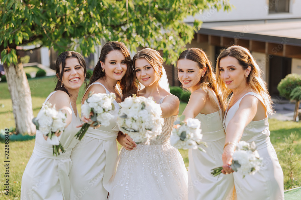 A brunette bride and her bridesmaids in identical white dresses are ...