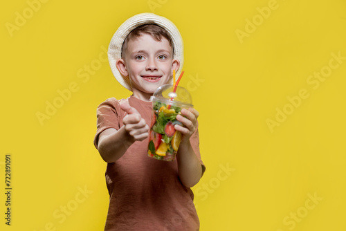 European boy in a hat, summer t-shirt with lemonade on yellow background.