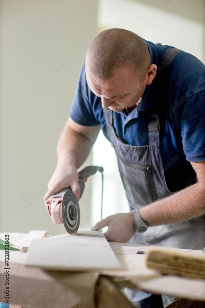 Professional tiler cutting tile with angle grinder. Construction, renovation, repair apartment. Professional tiler cutting tile with angle grinder. Construction, renovation, repair apartment.