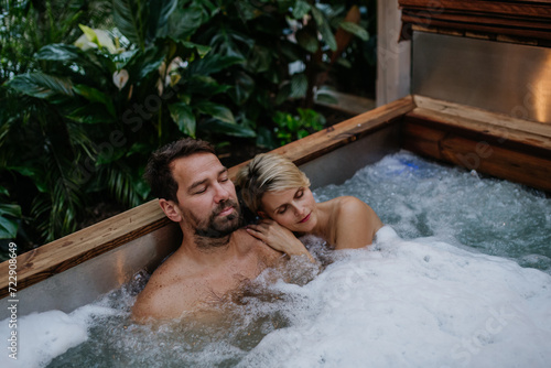 Beautiful mature couple relaxing in hot tub, enjoying romantic wellness weekend in spa. Concept of Valentine's Day.