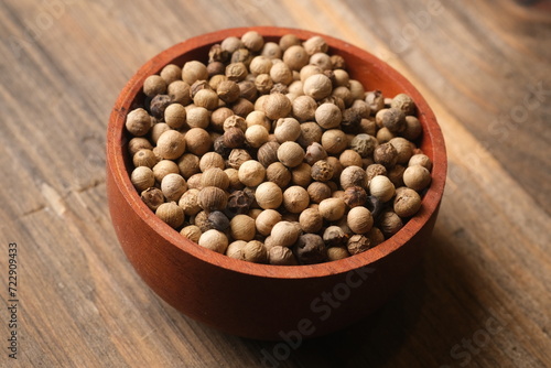 white pepper in the wooden bowl. pepper is a flowering vine in the family Piperaceae, cultivated for its fruit, which is usually dried and used as a spice and seasoning. Piper nigrum. 