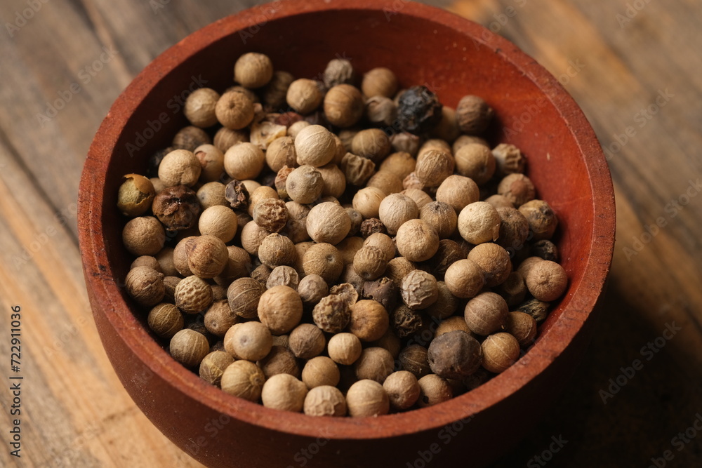 white pepper in the wooden bowl. pepper is a flowering vine in the family Piperaceae, cultivated for its fruit, which is usually dried and used as a spice and seasoning. Piper nigrum white pepper in the wooden bowl. pepper is a flowering vine in the family Piperaceae, cultivated for its fruit, which is usually dried and used as a spice and seasoning. Piper nigrum