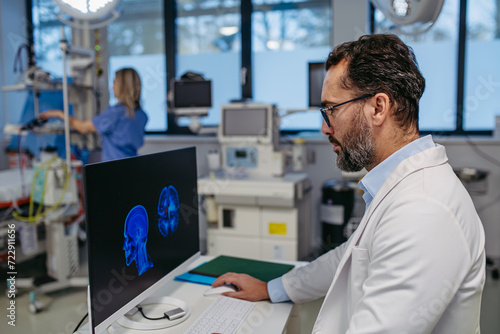 Portrait of ER doctor in hospital working in emergency room. Healthcare worker looking at MRI scan on medical computer in emergency room. photo