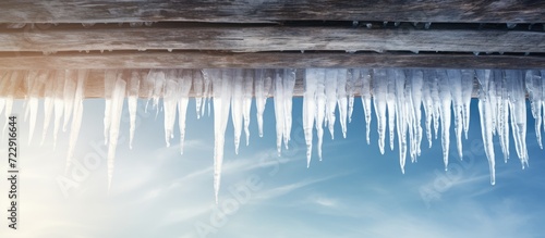 Icicles hang from the roof against the blue sky. Creative Banner. Copyspace image