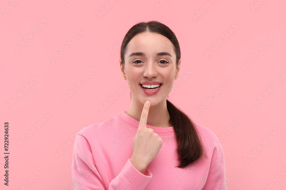 Beautiful woman showing her clean teeth and smiling on pink background Beautiful woman showing her clean teeth and smiling on pink background