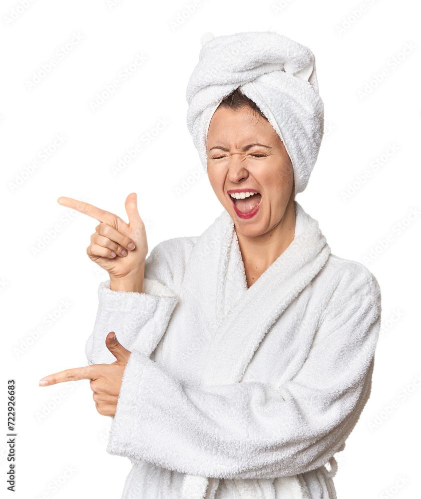 Caucasian woman in bathrobe and towel pointing with forefingers to a copy space, expressing excitement and desire. Caucasian woman in bathrobe and towel pointing with forefingers to a copy space, expressing excitement and desire.