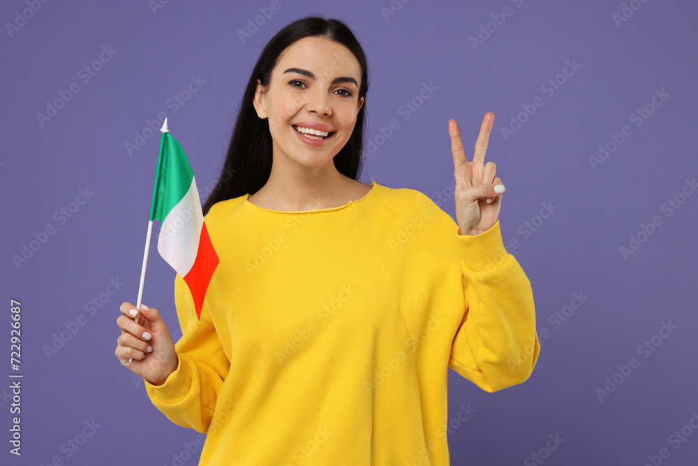 Happy young woman with flag of Italy showing V-sign on violet background Happy young woman with flag of Italy showing V-sign on violet background