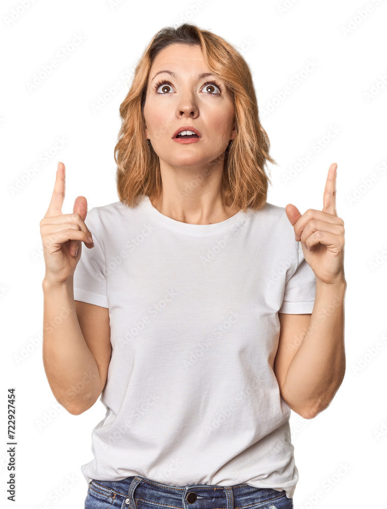 Blonde middle-aged Caucasian woman in studio pointing upside with opened mouth. Blonde middle-aged Caucasian woman in studio pointing upside with opened mouth.