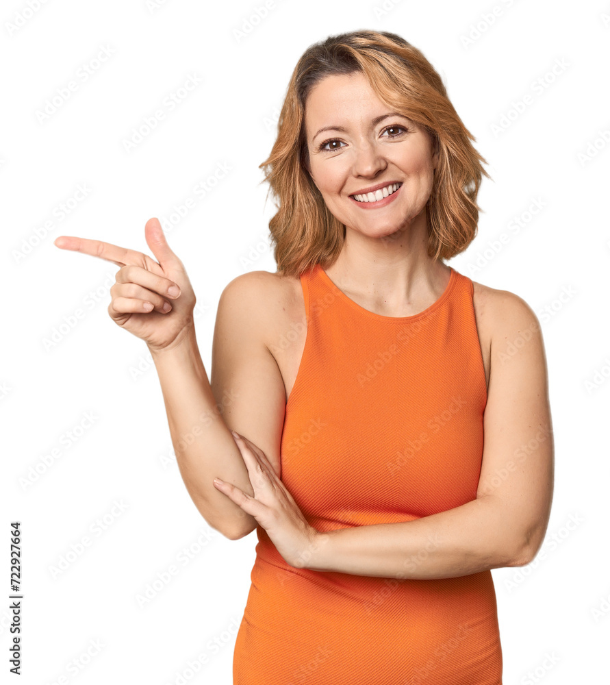 Blonde middle-aged Caucasian woman in studio smiling cheerfully pointing with forefinger away. Blonde middle-aged Caucasian woman in studio smiling cheerfully pointing with forefinger away.