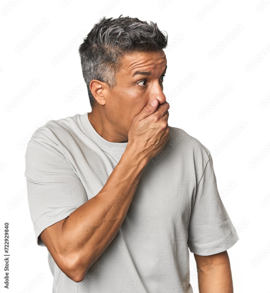Middle-aged Latino man thoughtful looking to a copy space covering mouth with hand. Middle-aged Latino man thoughtful looking to a copy space covering mouth with hand.