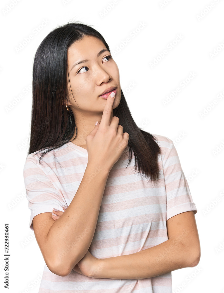 Young Chinese woman in studio setting looking sideways with doubtful and skeptical expression. Young Chinese woman in studio setting looking sideways with doubtful and skeptical expression.