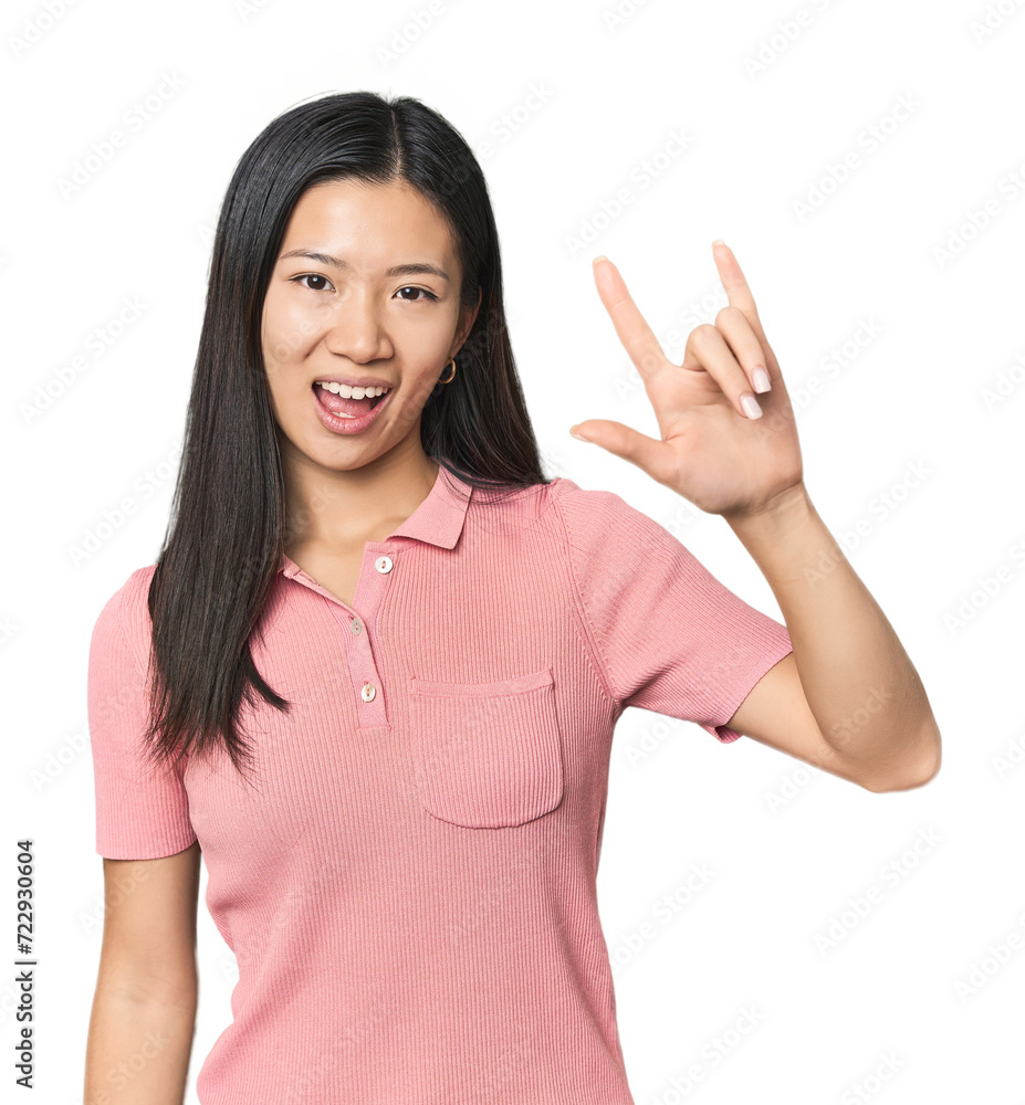 Young Chinese woman in studio setting showing a horns gesture as a revolution concept. Young Chinese woman in studio setting showing a horns gesture as a revolution concept.