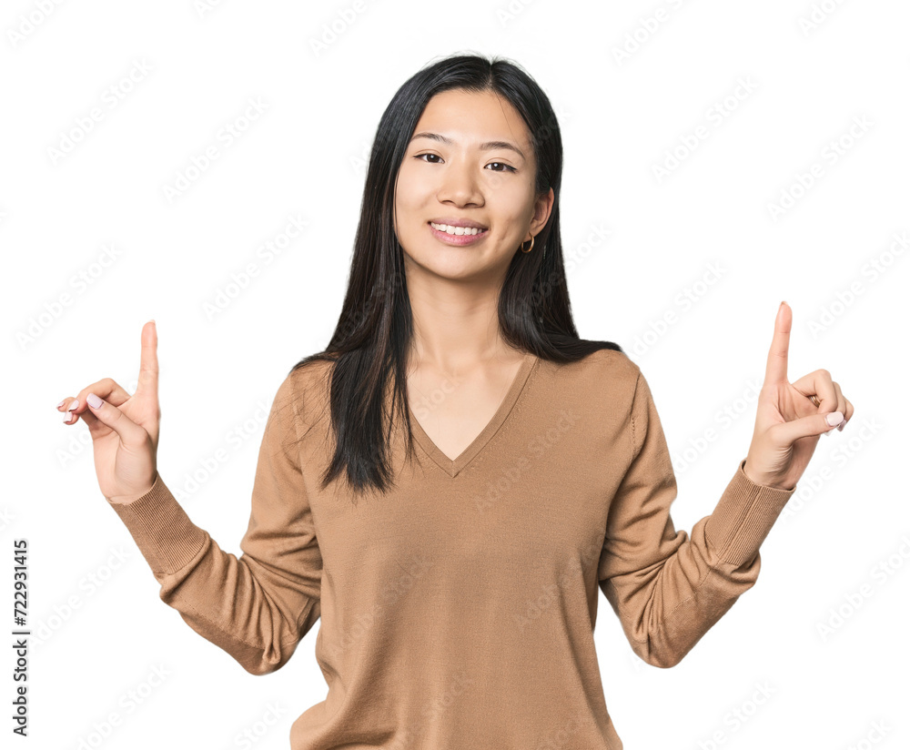Young Chinese woman in studio setting indicates with both fore fingers up showing a blank space. Young Chinese woman in studio setting indicates with both fore fingers up showing a blank space.