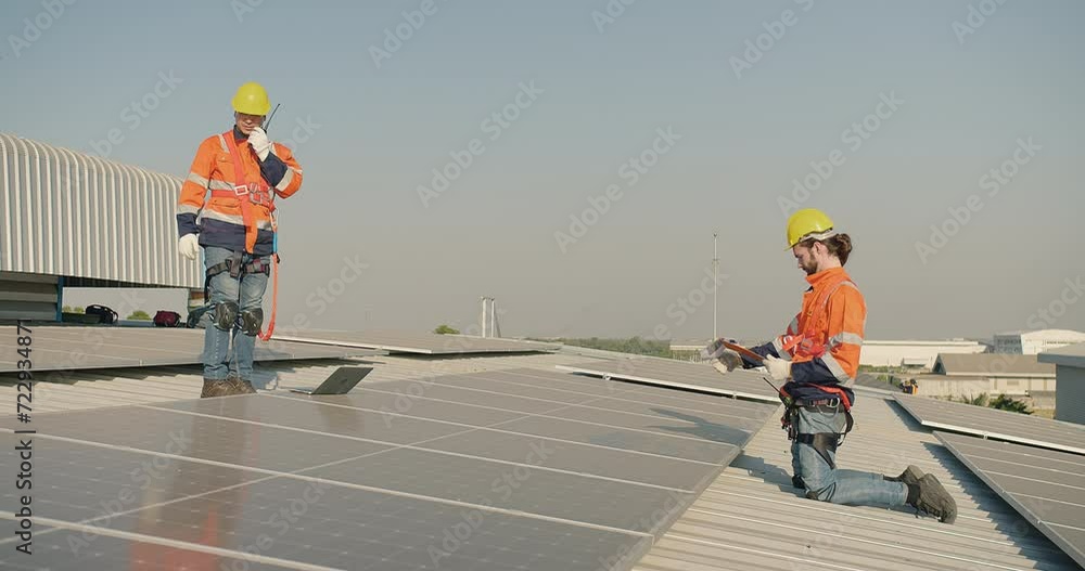 Two engineers technicians in safety gear are inspecting solar panels on solar panel roof installation Two engineers technicians in safety gear are inspecting solar panels on solar panel roof installation