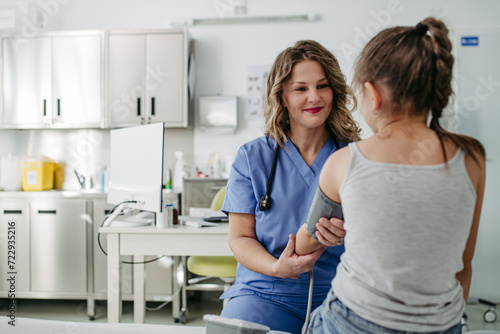 Φωτογραφία Doctor examining young girl, measuring blood pressure, using medical blood pressure monitor