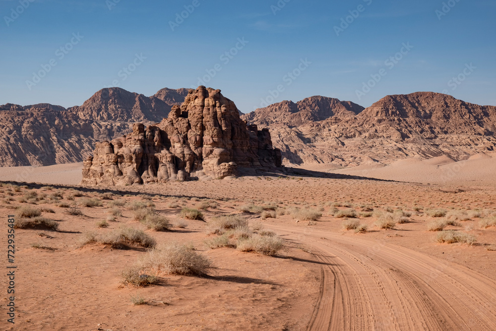 A dusty dirt road stretches through the arid landscape of the Wadi Rum desert in Jordan. A dusty dirt road stretches through the arid landscape of the Wadi Rum desert in Jordan.
