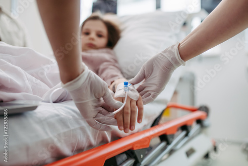 Close up of nurse insering IV cannula in little girl hand. IV, intravenous therapy for child patient.