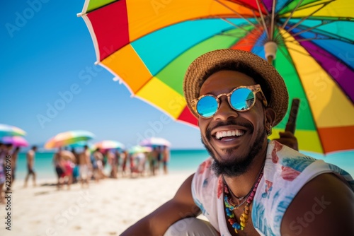 happy african american man on the beach in summer against the background of the sea or ocean and colorful umbrella