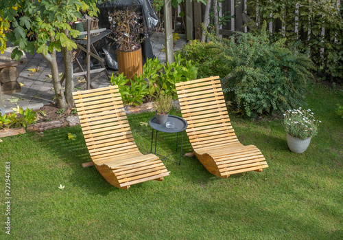 Two wooden deck chairs on the lawn in the backyard of a house