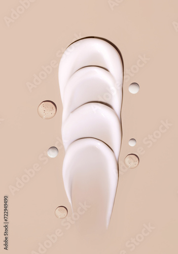 cosmetic smears of creamy texture drops of tonic serum on a beige background