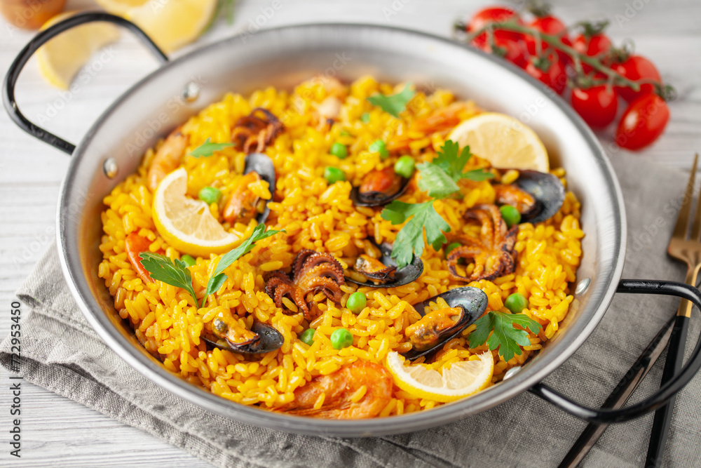 Traditional spanish seafood paella with rice, mussels, shrimps in a pan on wooden background.