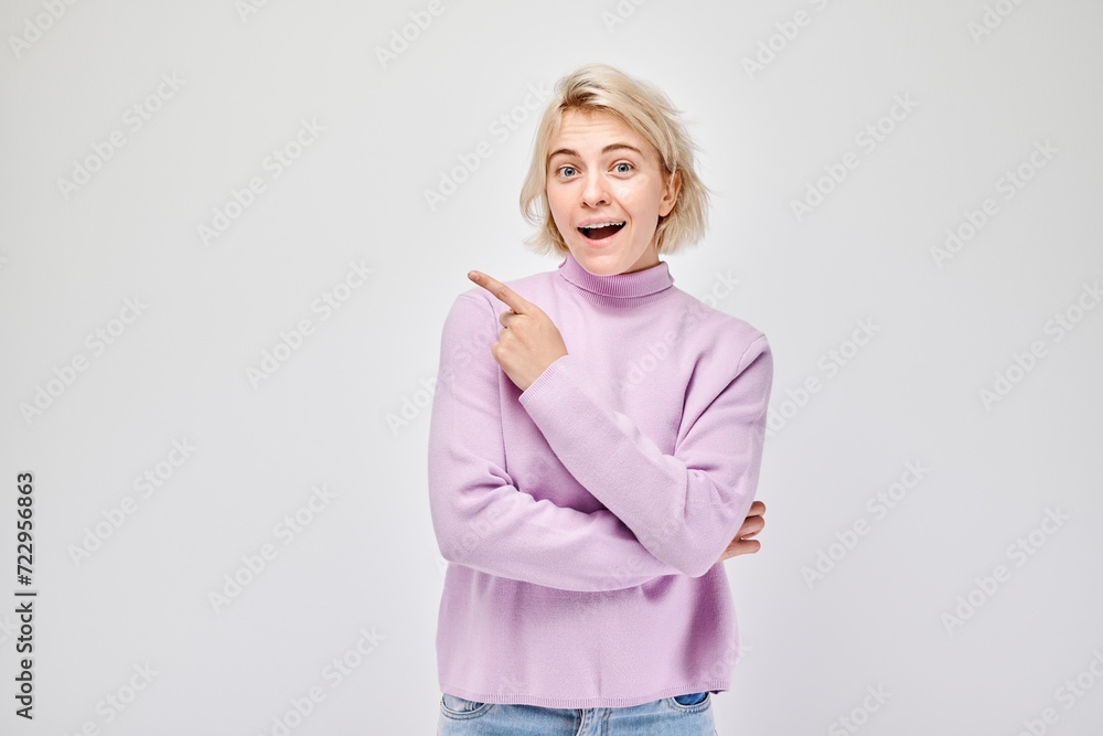 Young blond woman in casual pointing aside finger, demonstrating empty space for product or text isolated on white studio background. Young blond woman in casual pointing aside finger, demonstrating empty space for product or text isolated on white studio background.